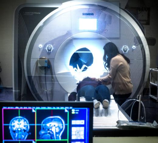 Photo of a female researcher placing another individual in an MRI machine at the Center for Advanced Brain Imaging