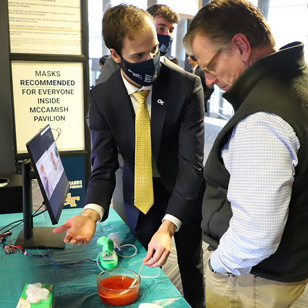 Maximilian Hollister explains the uDrain device to an attendee at the Fall 2021 Capstone Design Expo. The uDrain helps post-operative patients keep their surgical drains unclogged without any uncomfortable prodding and pulling. The handheld device aims to help patients avoid infection or other complications. (Photo: Joshua Stewart)