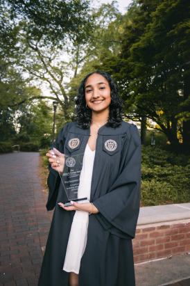 Photo of Sriya Surapaneni Wearing her Graduation Gown and Holding the Helen Grenga Award