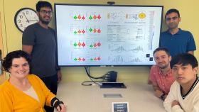 Cassie Mitchell at a table with her Ph.D. students. On the screen above the table is a data slide showing their work on an integrative machine learning algorithm to predict risk of neurodegenerative disease progression based on patient proteins, genotype, demographics, cognitive testing, and medical history. Clockwise from top left are Irfan Al-Hussaini , Raghav Tandon, David Kartchner, Albert Lee, and Mitchell. (Photo Courtesy: Cassie Mitchell)