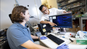 phd machine learning gatech A male student with a blue shirt sits in front of a computer moving the computer mouse as a male faculty member, standing behind the computer screen, points to a digital DNA sequence on the screen.