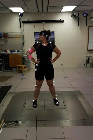 Fry dons a set of motion capture markers (illuminated dots) and electromyography (EMG) electrodes (pink bands) to participate in Drnach's human-human interaction study. The markers reflect light from a camera so Drnach can measure the locations of the body segments.