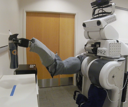 Showing its capabilities as a body surrogate, a PR2 controlled remotely by an individual with profound motor deficits picks up a cup in a research laboratory at the Georgia Institute of Technology. (Credit: Phillip Grice, Georgia Tech)