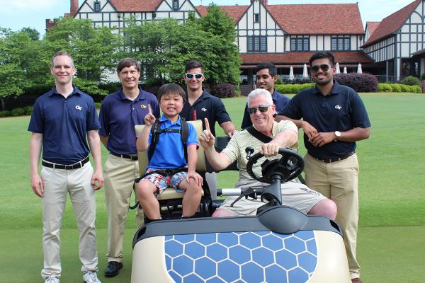 Faculty and student capstone design team members with Bobby Baird and CSF Chairman Paul Farrell driving the golf car.