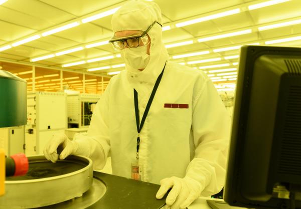 Georgia Tech graduate research assistant Mason Chilmonczyk examines a device after a plasma etch step in a reactive ion etching tool. The work was being done in the Institute of Electronics and Nanotechnology’s Marcus Building clean room. (Credit: Rob Felt, Georgia Tech)