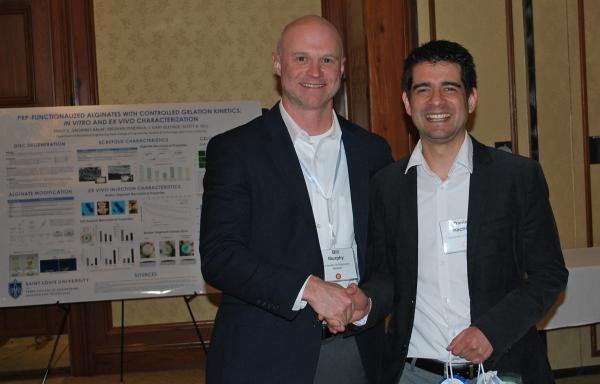 Bill Murphy from the University of Wisconsin congratulates University of Pittsburgh grad student Daniel Hachim, who took first place in the research poster competition.