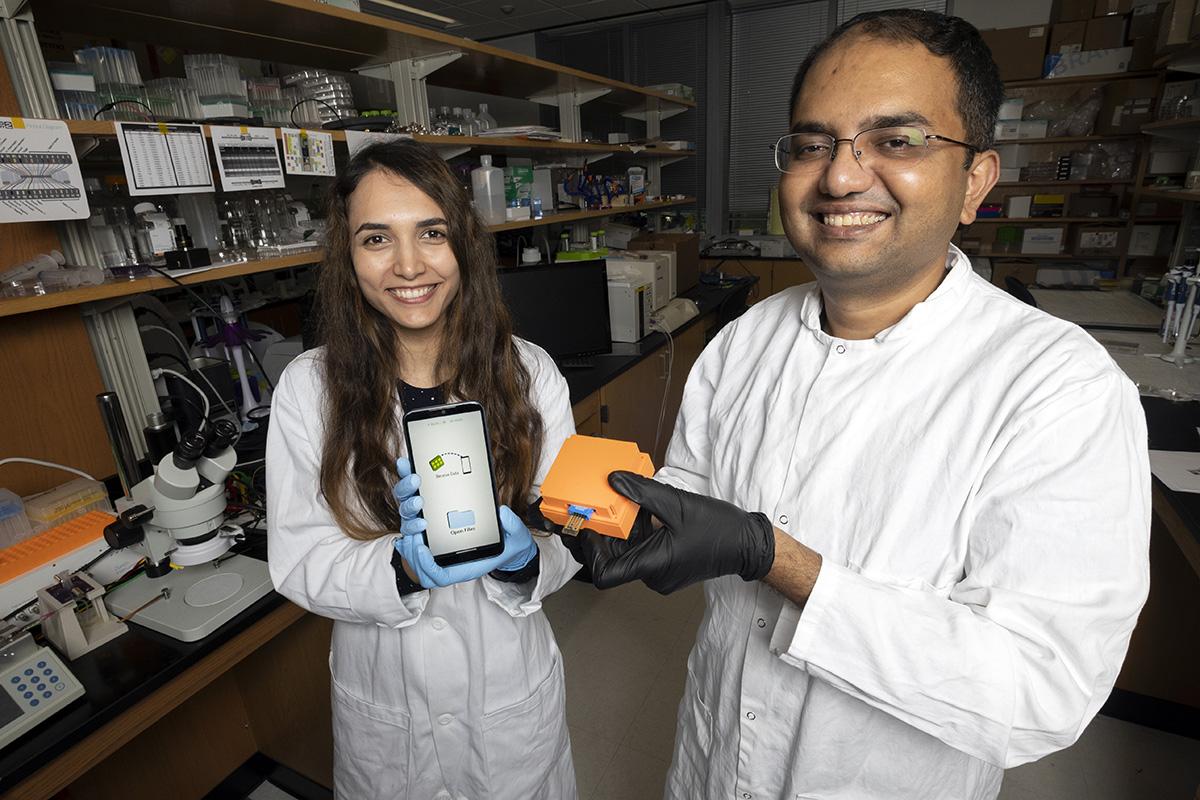 Postdoctoral fellow Neda Rafat and Assistant Professor Aniruddh Sarkar with the Bluetooth reader and smartphone app their team developed to display test results from a new electronic Covid-19 test chip. (Photo: Candler Hobbs)